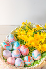 Close Up of Basket of Hand Painted Easter Eggs with Daffodils on Table Vertical with Copy Space