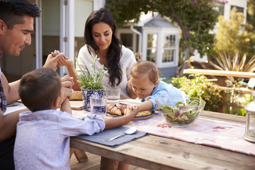 Family At Home Eating Outdoor Meal In Garden Together