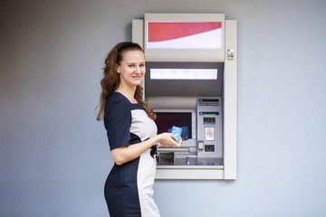 Fototapeta na wymiar Young woman inserting a credit card to ATM