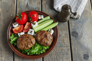  fried cutlets in plate with vegetables on wooden table