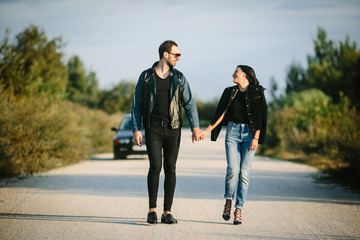 Young happy romantic couple walking along road