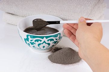 bowl of black clay mask with brush at home skin care