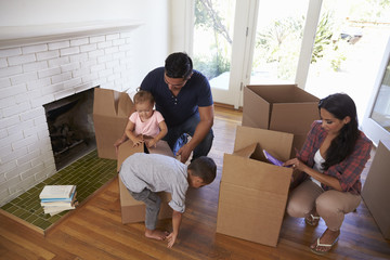 Family Unpacking Boxes In New Home On Moving Day