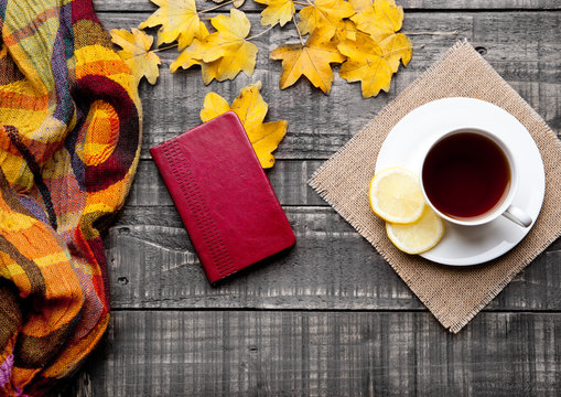 Cup of tea with lemon with scarf and autumn leaves