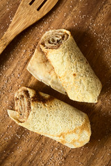 Crepe rolls filled with cinnamon and sugar, photographed overhead on wood with natural light (Selective Focus, Focus on the top of the rolls)