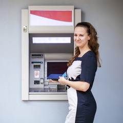 Young woman inserting a credit card to ATM