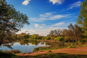 A beautiful view by the lake during sunset on a summer evening. majestic picturesque sky are reflecting from the still water. Dramatic scenic summer scene. Beauty in the world