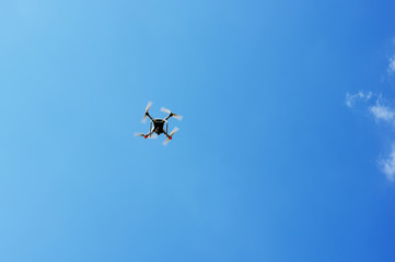 drone quad copter with digital camera flying hovering in the blue sky
