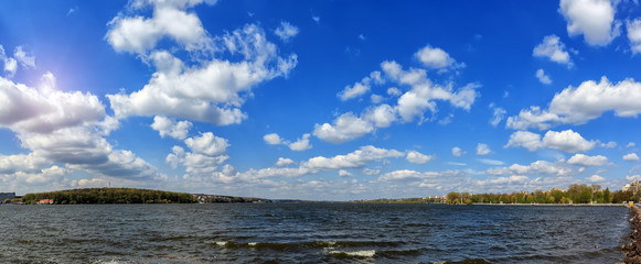 breathtaking scenery. many fluffy clouds in the blue sky over the water. hectic urban lake. panorama