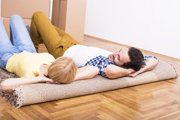 Young couple laying on carpet in new home. Home, people, moving and real estate concept