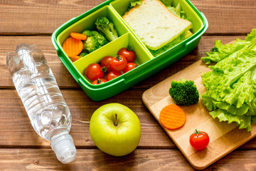lunch box for kid with fresh vegetables on wooden background