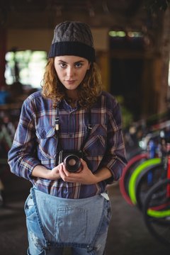 Woman adjusting vintage camera in bicycle shop
