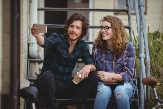 Couple sitting on stairs and taking selfie