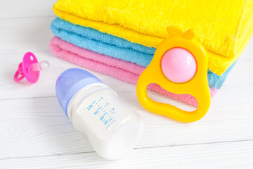 baby bottle with milk and towel on wooden background