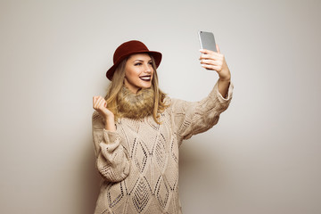 Beautiful modern young woman in autumn outfit taking a selfie