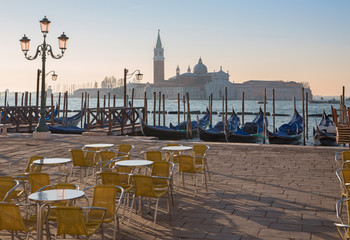 Venice - Chairs on Saint Mark square and San Giorgio Maggiore church in background in morning light.