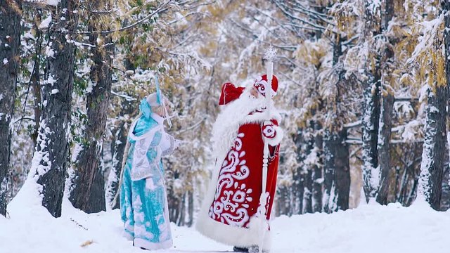 Father Frost picking up the bag with New Year gifts, and snowflake helping him