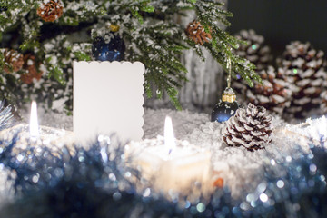 Christmas still life is with snow. White plate for congratulations is near the Christmas tree.  