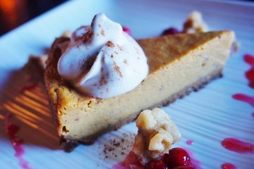 A vegan pumpkin pie cheesecake with coconut whipped cream and fresh cranberries