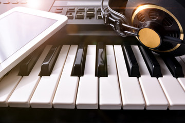 Obraz premium Electronic piano with headphones and tablet in studio front