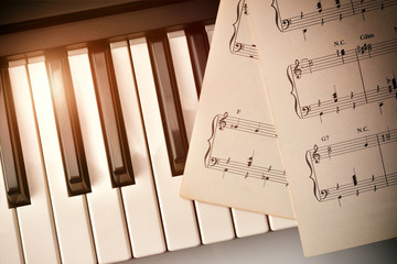 Obraz premium Piano keyboard with golden shine and sheet music top diagonal