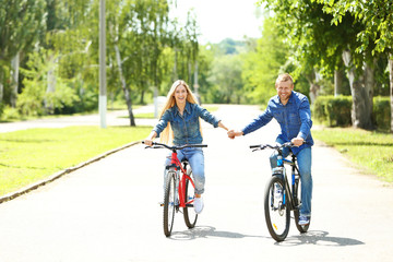 Obraz premium Happy couple riding bicycles in the park