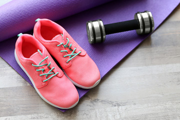 Comfortable sneakers with sport tools on floor