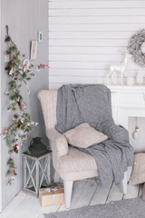 Stylish Christmas interior decorated in gray colors. Comfort home. Armchair with fabric upholstery