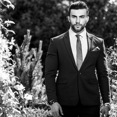 Black-white outdoor portrait of elegant handsome man in classical suit.