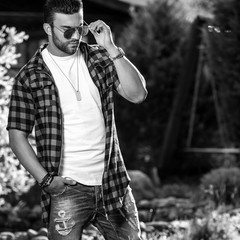 Black-white outdoor portrait of sporty stylish handsome man in casual clothes.