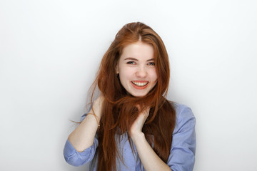 Portrait of cute redhead girl wearing blue striped shirt smiling with happiness and joy while posing against white studio background. 