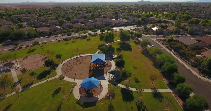 A daytime aerial establishing shot of a typical Arizona neighborhood park.  	