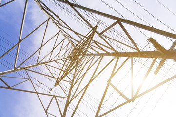 Obraz premium Silhouette shot of electricity pylons, natural golden sunlight at background.