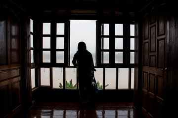 Silhouette of a young woman open window