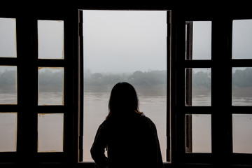 Silhouette of a young woman open window