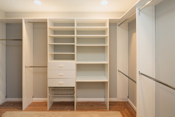 Big empty walk in wardrobe in luxurious house with installed shelves / drawer.