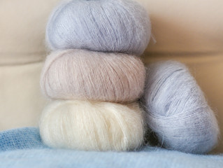 Thin fluffy skeins of wool for knitting a pale pink, blue and be