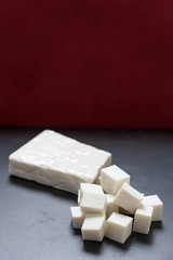 Buffalo paneer Indian cheese on black slate cutting chopping board counter in one large piece and...