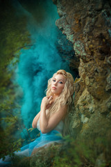 Fototapeta na wymiar Сказочная девушка на скале в голубом дыму