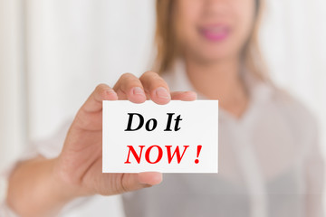 Do it now ! message word on card in hand of Friendly woman hand