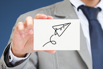 Businessman hand holding card with paper rocket.
