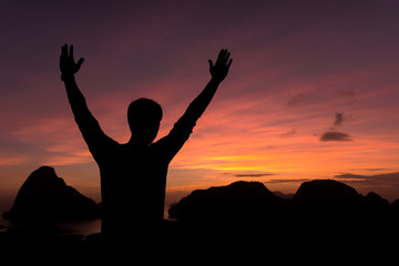  silhouette of man standing and open arms raised towards sky con