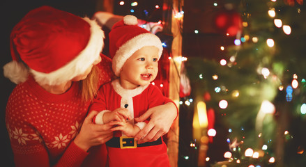 happy family mother and baby near Christmas tree in holiday nigh