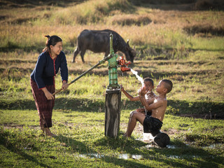 Mother her sons shower outdoor from Groundwater pump, Countrysid