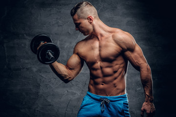 Athletic young male holds dumbbell.