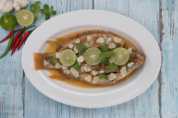 steamed fish with chili and lemon on blue wood table, thai food