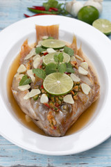 steamed fish with chili and lemon on blue wood table, thai food