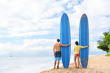 Two people young couple surfers standing with long blue surfboards on hawaii Kaanapali beach after surf class. Fun surfing sport activity on Maui touristic beach for summer vacations.