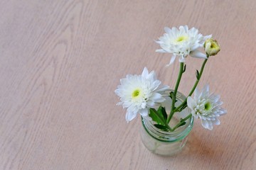 Soft focus and blurry Top view White flowers in a glass vase  on wooden background. retro and vintage tone, hipster style.