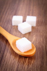 Cubes of sugar on wooden background, ingredient for cooking